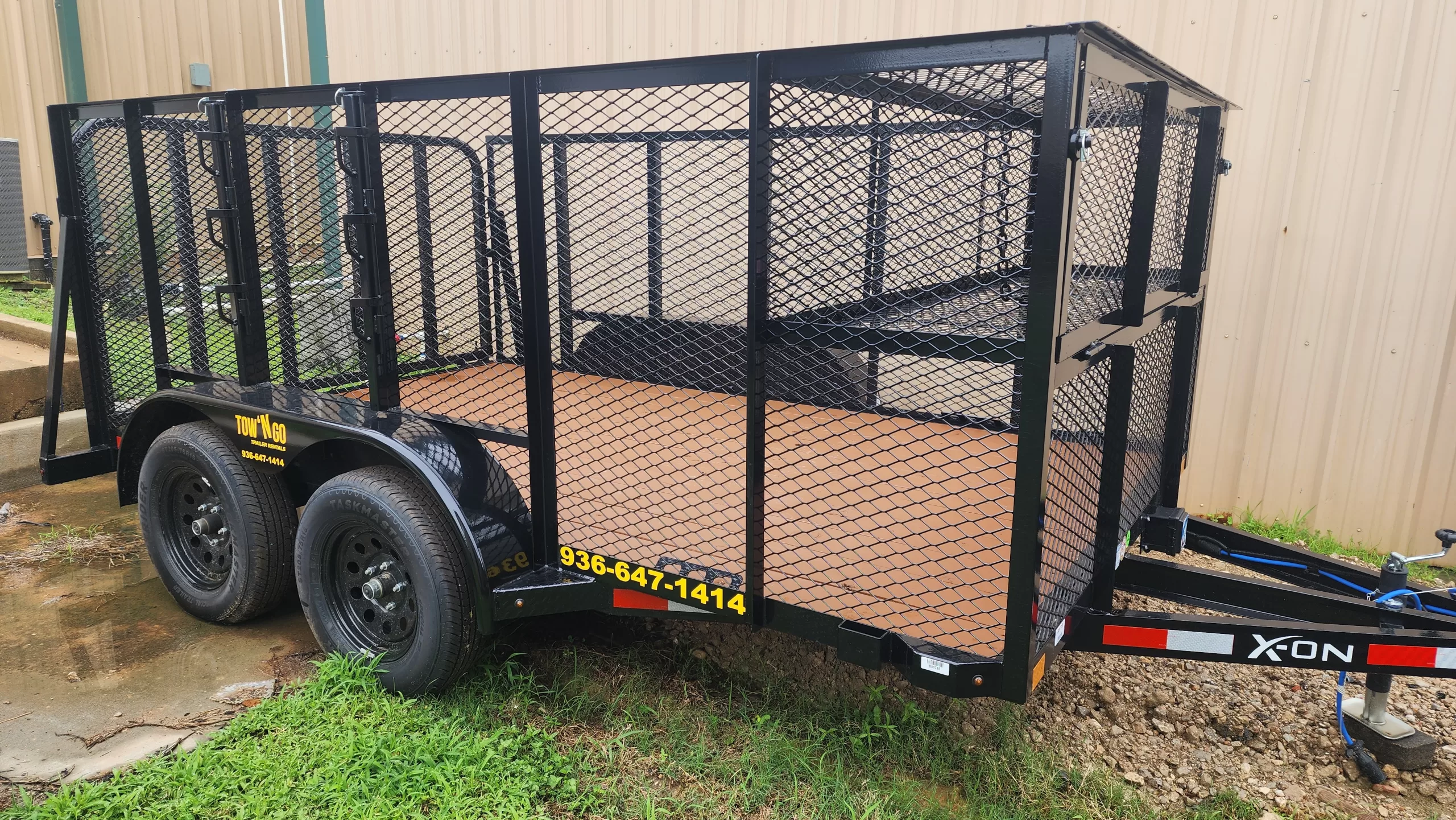 A 12-foot landscape trailer featuring 4-foot tall expanded metal mesh sides, a reinforced rear ramp gate, and a heavy-duty single axle for hauling lawn equipment and debris.