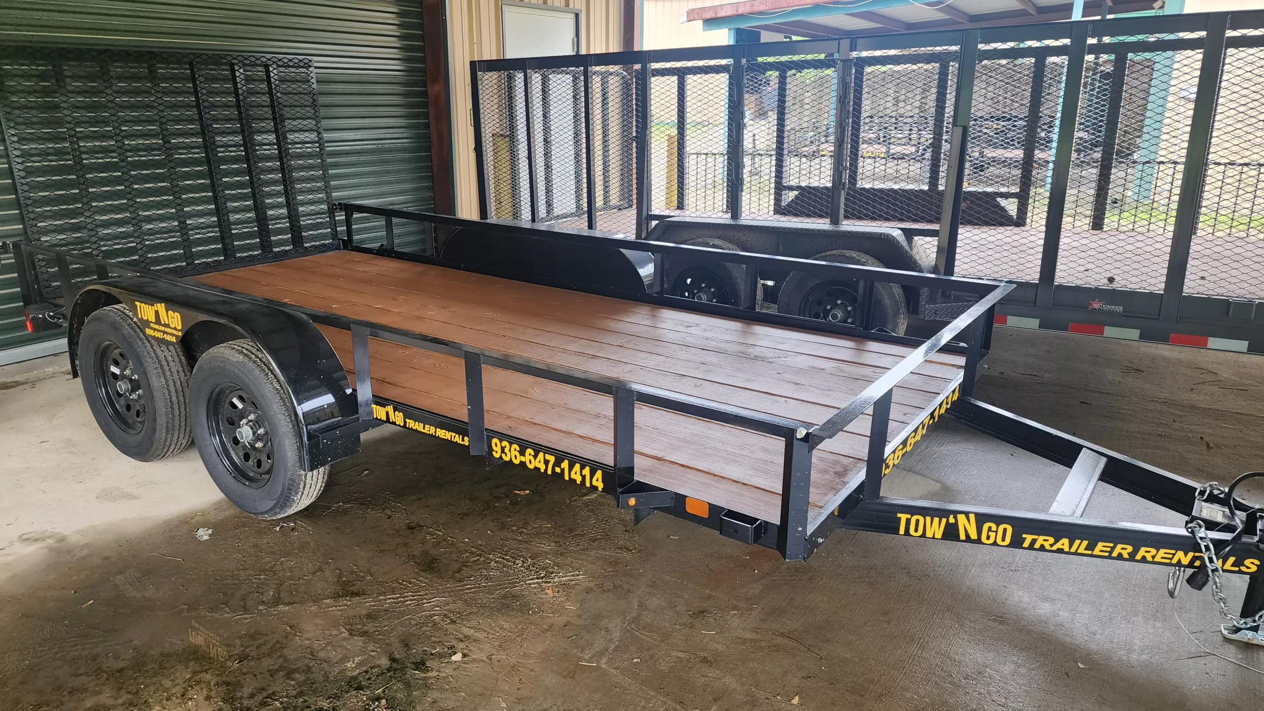 A 14-foot tandem-axle utility trailer with a heavy-duty mesh ramp, side rails, and a black powder-coated finish.
